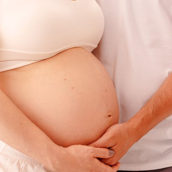 Close-up of a pregnant woman's hands on her belly, showing connection.